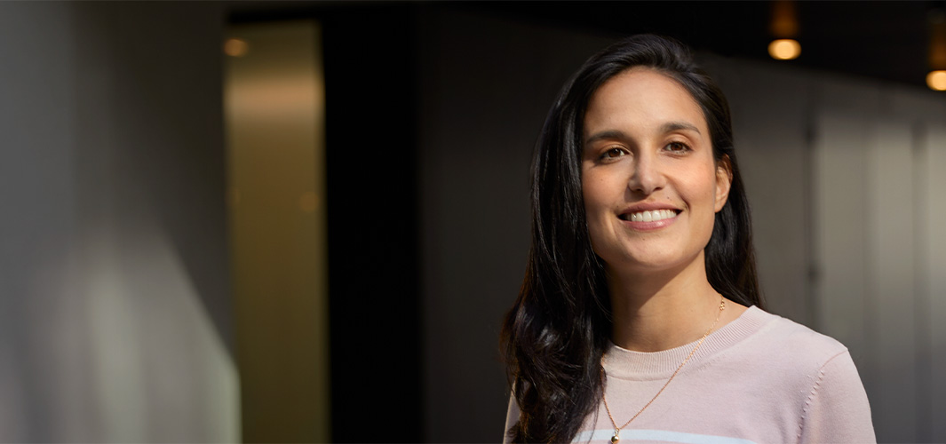 Camila 面帶微笑站在室內辦公空間。