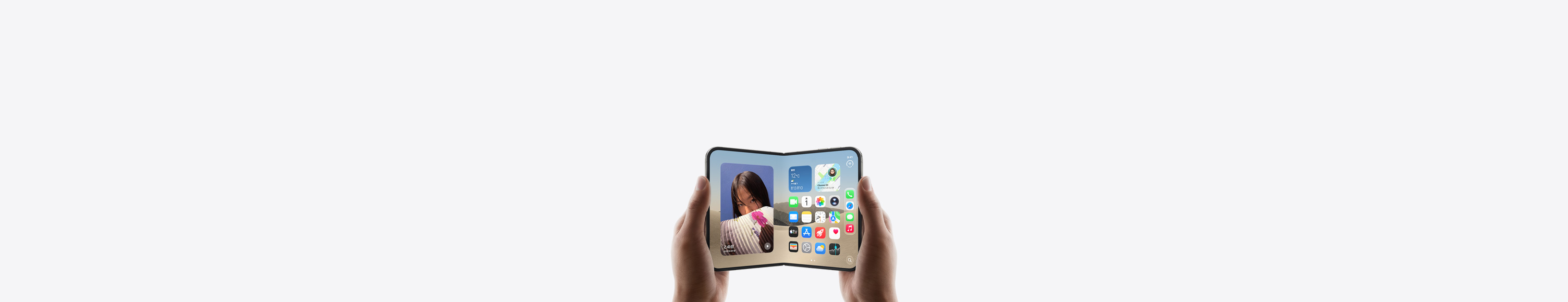 横向きに開いた状態のiPhone Duoを両手で持っている。インナーディスプレイにホーム画面が表示されている
