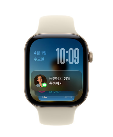 라이트 블러시 밴드가 장착된 로즈 골드 색상 Apple Watch Series 11. 왼쪽 상단에 날짜, 오른쪽 상단에 시간, 하단에 메시지 위젯이 표시된 모습