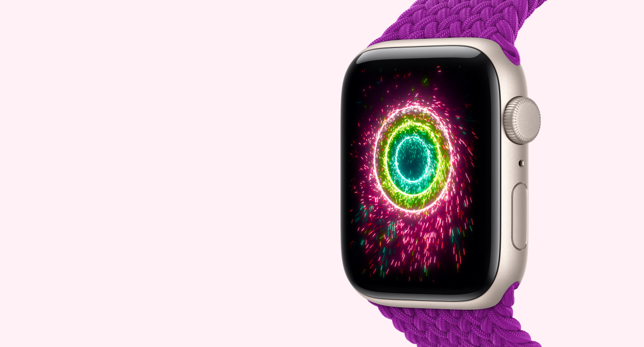 Apple Watch SE 3, starlight color aluminum case connected to magenta color Braided Solo Loop band, screen shows Activity rings styled as sparklers, pink, lime green, light blue concentric rings