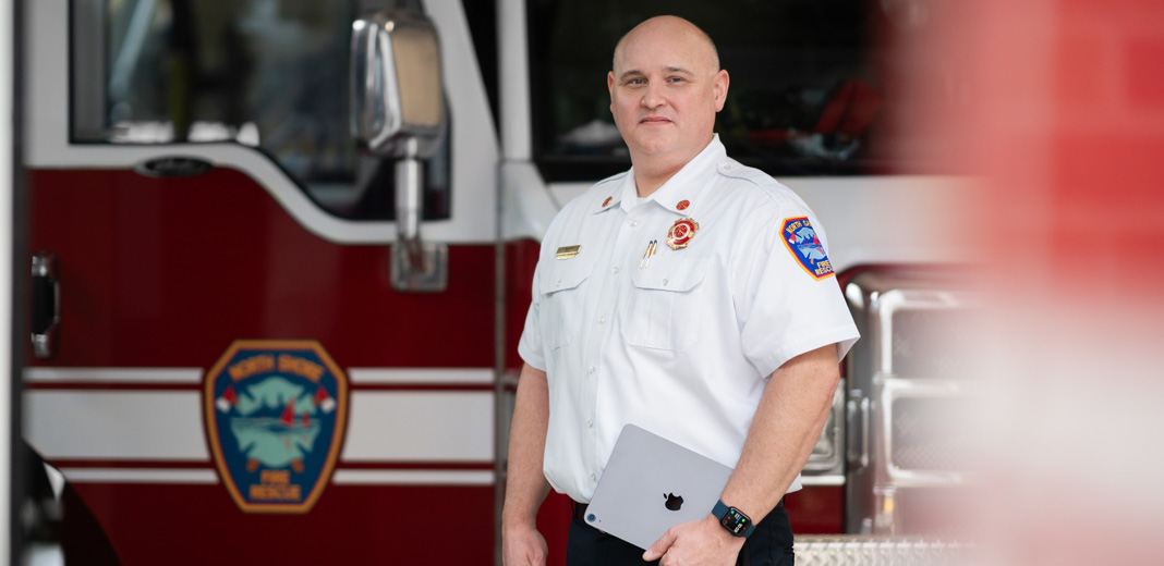 Le chef du service d’incendie devant un camion de pompiers, un iPad à la main et une Apple Watch au poignet